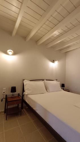 a bedroom with a large white bed and a table at Lesvos Tower House Komninos in Sígrion