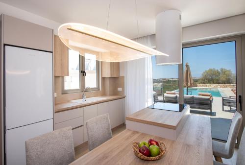 a kitchen and dining room with a table and a bowl of fruit at Calmo Luxury Villas, with Pool Tranquil Elegance, By ThinkVilla in Lamerianá