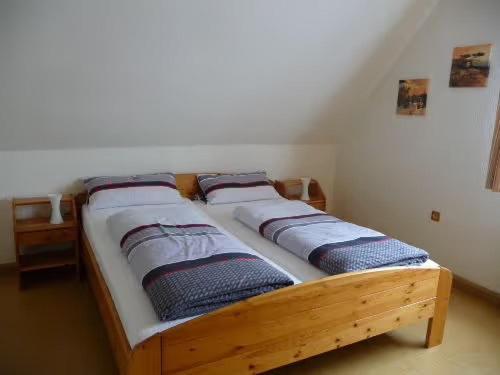 a wooden bed with four pillows on it in a room at Ferienwohnung Wassergartenparadies in Harsdorf