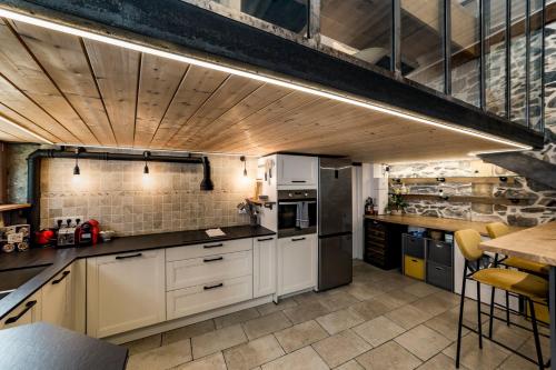 une cuisine avec des armoires blanches et un plafond en bois dans l'établissement Le duplex des pentes AIL, à Lyon