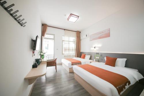 a hotel room with two beds and a desk at 莆田市湄洲岛蓝湾半岛宾馆妈祖祖庙店 in Putian