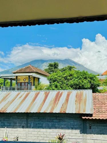 a house with a rusty roof with mountains in the background at Shan Hai Jing Hotel in Tulamben
