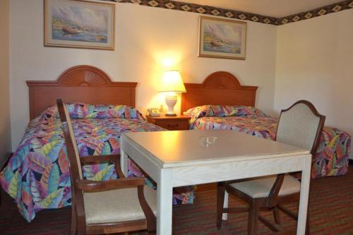 een slaapkamer met 2 bedden en een tafel en stoelen bij Motel Jesup in Jesup