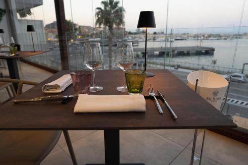 a wooden table with wine glasses and napkin on it at Petit Hotel in Milazzo