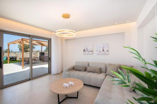 a living room with a couch and a table at Calmo Luxury Villas, with Pool Tranquil Elegance, By ThinkVilla in Lamerianá