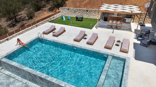 an overhead view of a swimming pool with chaise lounges at Calmo Luxury Villas, with Pool Tranquil Elegance, By ThinkVilla in Lamerianá
