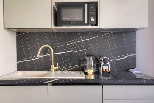 un comptoir de cuisine avec un évier et un micro-ondes dans l'établissement Studio confortable près de la Croix-Rousse, à Caluire-et-Cuire