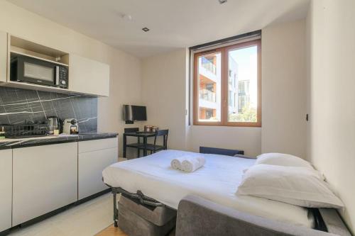 une chambre avec un lit dans une cuisine équipée d'un four micro-ondes dans l'établissement Studio confortable près de la Croix-Rousse, à Caluire-et-Cuire