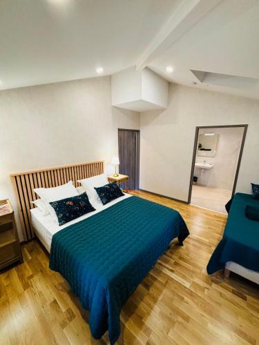 une chambre avec un grand lit avec une couverture bleue dans l'établissement Les pierres roses, à Coise