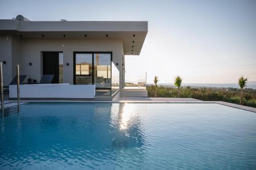 une villa avec piscine devant une maison dans l'établissement Aetheria & Aura Suites by Temma Villas, à Chersónissos