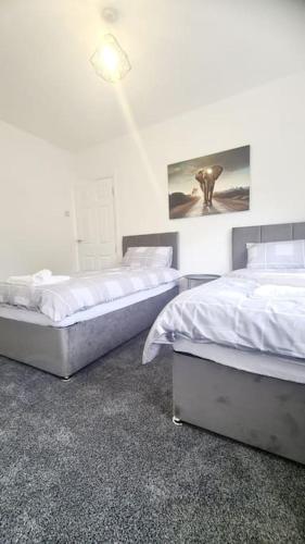a bedroom with two beds and a light on the wall at Freshen - up Stays Birmingham Spacious 3-Bed Contractor & Insurance Accommodation Parking Garden in Birmingham