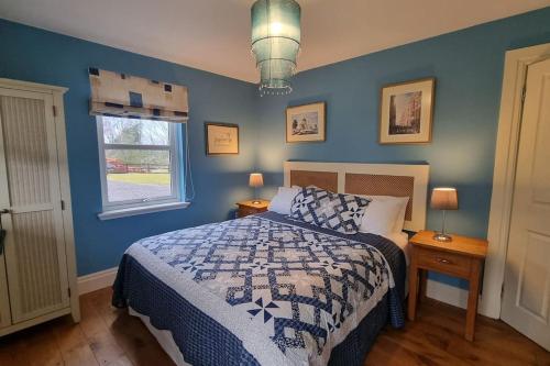 a bedroom with a bed and a blue wall at Heath House Loch Ness in Errogie