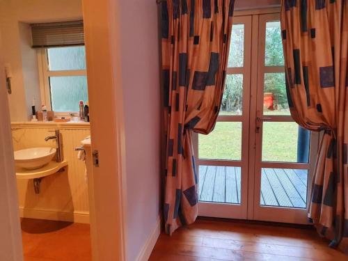 a bathroom with a sink and a door with a window at Heath House Loch Ness in Errogie