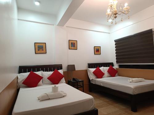two beds in a room with red and white pillows at Jil's Apartelle in Tagaytay