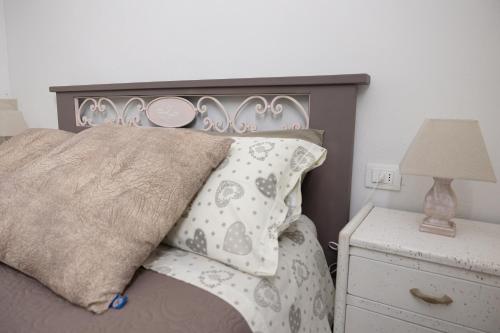 a bed with a gray headboard and a night stand with a lamp at Di Colle in Colle - Agriturismo in Passignano sul Trasimeno