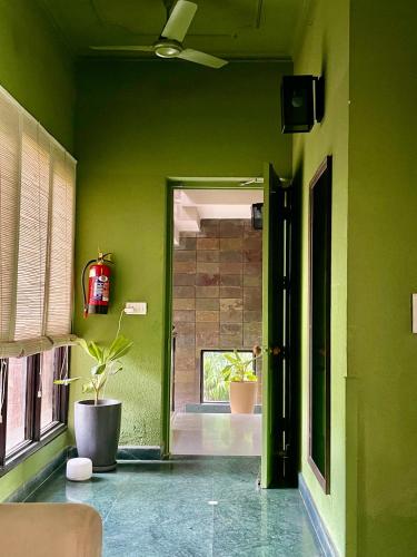 a hallway with green walls and a door with plants at Firebrick Boutique Residences - GARNET HOUSE in Gurgaon