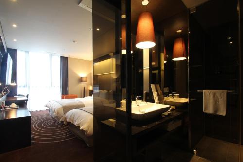a bathroom with a bed and a sink and a mirror at Best Louis Hamilton Hotel Haeundae in Busan