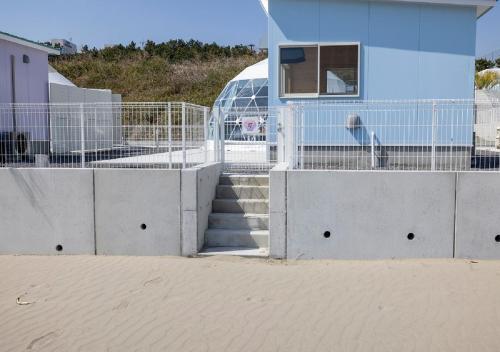 a building on the beach with stairs and a fence at Sugar Beach Oarai in Oarai