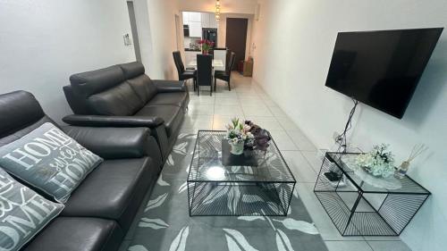 a living room with a black leather couch and two tables at Meritus - Perai in Perai