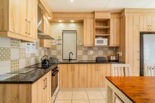 a kitchen with wooden cabinets and black counter tops at ATKV Goudini Spa in Rawsonville