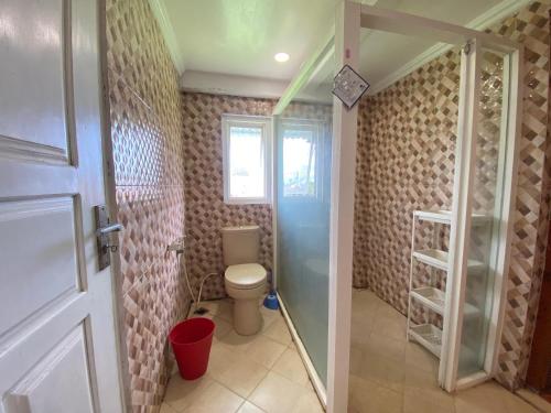 a bathroom with a toilet and a glass door at Super Wonderful 5 bedrooms with Bathroom Villa Marion Tomohon in Tomohon