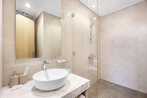 a bathroom with a white sink and a shower at Goldbest - Aykon City 2bdr in Dubai