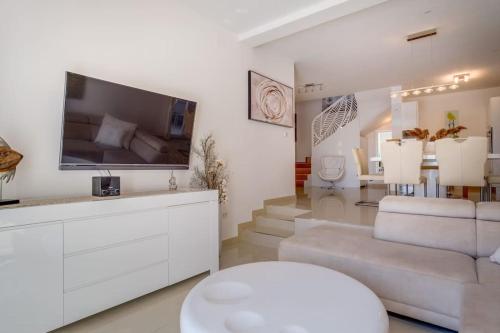 a living room with a large television and a white couch at Vila Blanka in Martinšćica