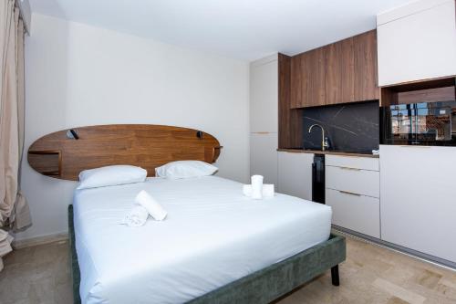 - une chambre avec un grand lit blanc et une tête de lit en bois dans l'établissement Studio Merlot - Welkeys, à Cannes
