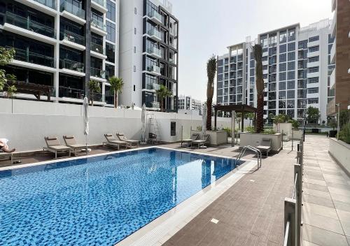 a swimming pool with chairs and a building at 1BR Gem with Pool 15 Mins to Downtown Dubai in Dubai