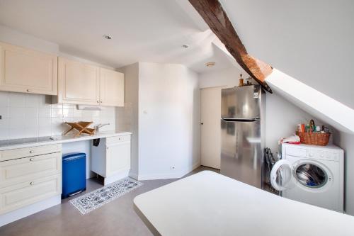 une cuisine avec des armoires blanches et une laveuse et une sécheuse dans l'établissement Nantes Mediathèque, grand T2 sous les toits, à Nantes