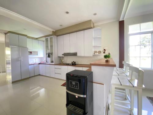 a kitchen with white cabinets and a black appliance at Super Wonderful 5 bedrooms with Bathroom Villa Marion Tomohon in Tomohon