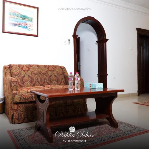 a living room with a table and a couch at Dahlia Sohar Hotel Apartments in Sohar