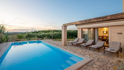 a swimming pool with chairs and a house at Villa Nira by Villas Holiday in Barat