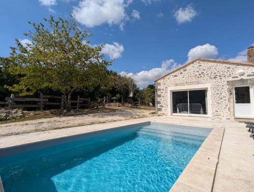 - une piscine en face d'une maison en pierre dans l'établissement La Maison De Mon Enfance et son Studio, à Magnac-Lavalette