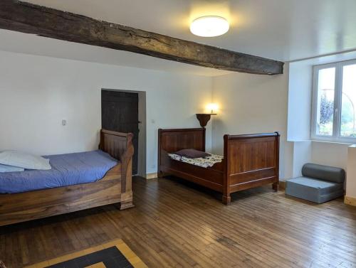 - une chambre avec 2 lits et une chaise dans l'établissement La Maison De Mon Enfance et son Studio, à Magnac-Lavalette