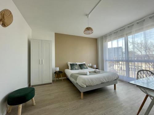 ein Schlafzimmer mit einem Bett und einem großen Fenster in der Unterkunft Rouen Saint Julien - L'Esprit village in Rouen