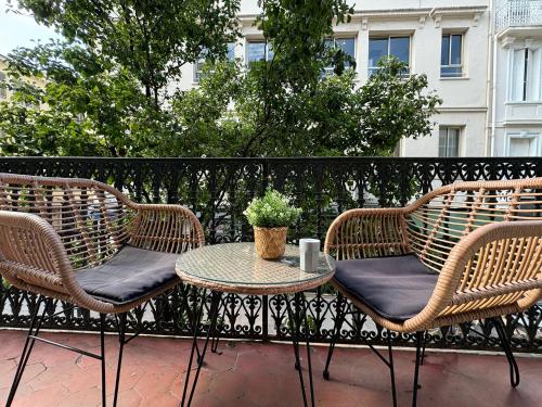 een patio met 3 rieten stoelen en een tafel bij Luxury Family 2BR - Prime Location, Walk to Beach & Shopping, Sunny Balcony - By Totolulu Cannes Hoche in Cannes