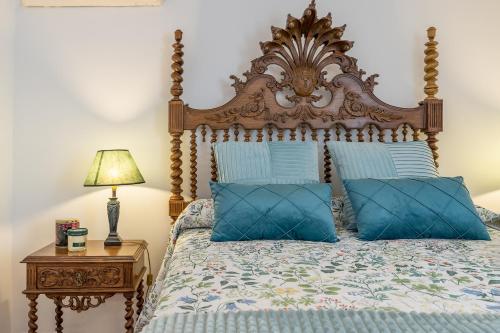 a bed with a wooden headboard and blue pillows at Carmen San Andrés in Granada