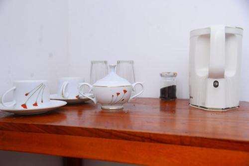 a wooden table with several tea cups and a coffee maker at Okeed Ella in Ella