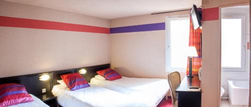 two beds in a room with red and blue stripes at Hôtel Saint Sauveur in Lourdes