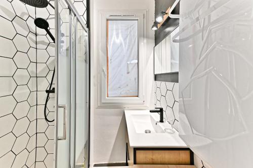 une salle de bain blanche avec un lavabo et un miroir dans l'établissement Séjour dans le Quartier Batignole Paris 17ème, à Paris