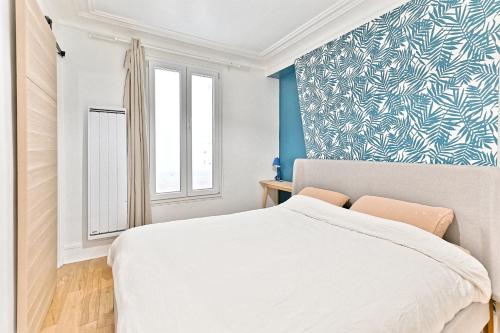 - une chambre avec un lit blanc et un mur bleu dans l'établissement Séjour dans le Quartier Batignole Paris 17ème, à Paris