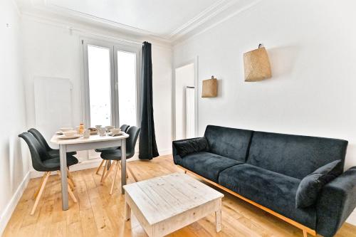 un salon avec un canapé noir et une table dans l'établissement Séjour dans le Quartier Batignole Paris 17ème, à Paris