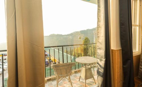 a balcony with a table and chairs and a view at Himalayan Suite in Dharamshala