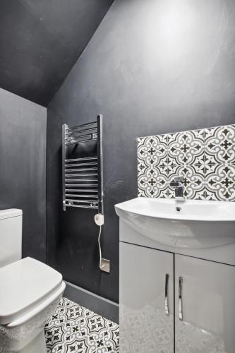 a bathroom with a white sink and a toilet at Cozy London Apartment in London