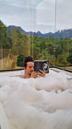 a man sitting in a bath tub reading a book at Casa de montanha com hidro no pé da serra in Orleans