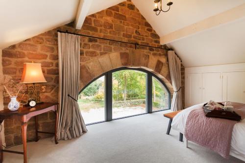 ein Schlafzimmer mit einer Steinmauer und einem Torbogen in der Unterkunft Rocking Stone Cottage in Matlock