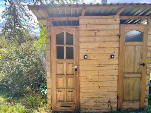 a wooden outhouse with a door in the grass at Dom Uzdrowisko in Tolkmicko