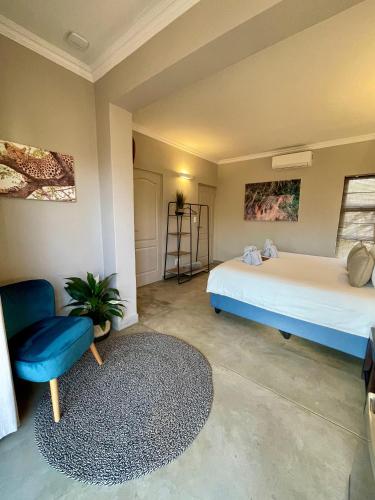 a bedroom with a bed and a blue chair at The Baobab Bush Lodge and Villa in Hoedspruit