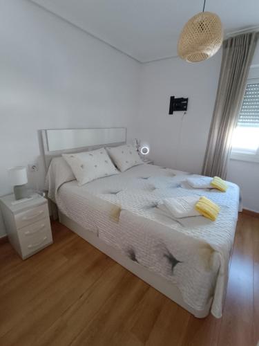 a bedroom with a white bed with yellow towels on it at Casa Teo. in Santa Pola